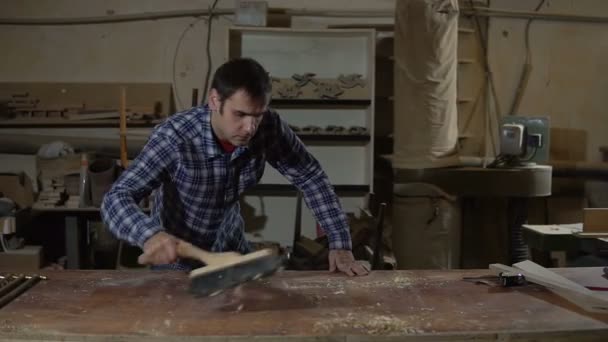 Homme dans un atelier de menuiserie nettoie la table de la sciure — Video