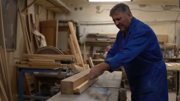 Carpintero en el trabajo en su taller, procesamiento de madera en una máquina de carpintería — Vídeos de Stock