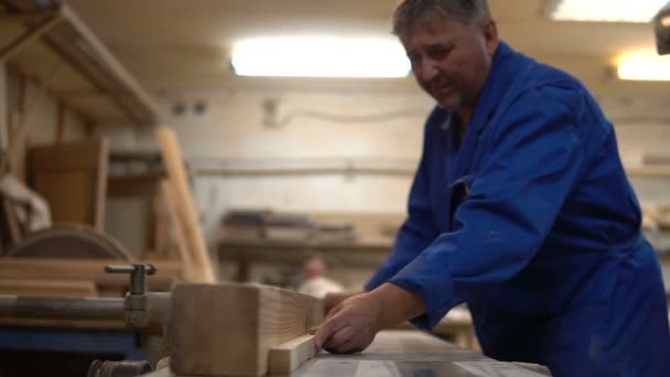 Carpintero en el trabajo en su taller, procesamiento de madera en una máquina de carpintería — Vídeos de Stock