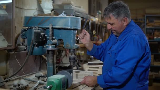 Сотрудник сверлит деталь в мастерской с помощью буровой машины — стоковое видео