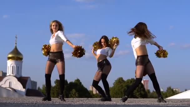 Тріо дівчата вболівальниці з помпонами танцюють на відкритому повітрі — стокове відео