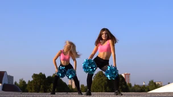 Två Flickor Cheerleaders Med Pomponger Dansa Utomhus Himmel Bakgrund — Stockvideo