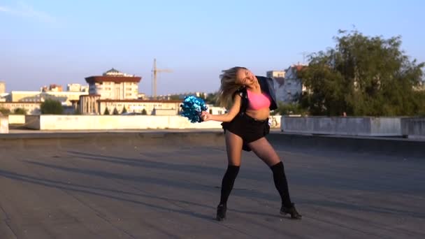 Girl cheerleader with pompoms dancing outdoors on the roof — Stock Video
