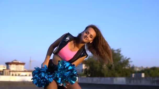 Девушка-чирлидер с помпонами танцует на крыше — стоковое видео