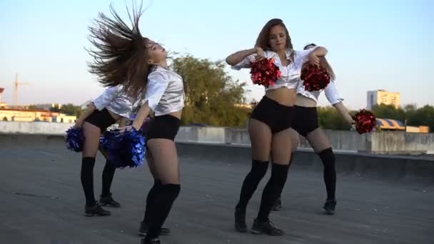 Вболівальники дівчата танцюють на даху під час заходу сонця — стокове відео