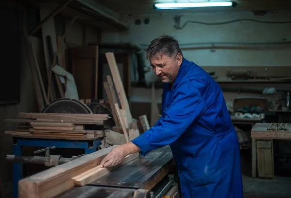 Carpenter at work at his workshop, wood processing on a woodworking machine in worshop