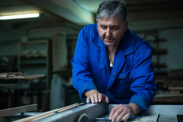 Carpenter at work at his workshop, wood processing on a woodworking machine in worshop