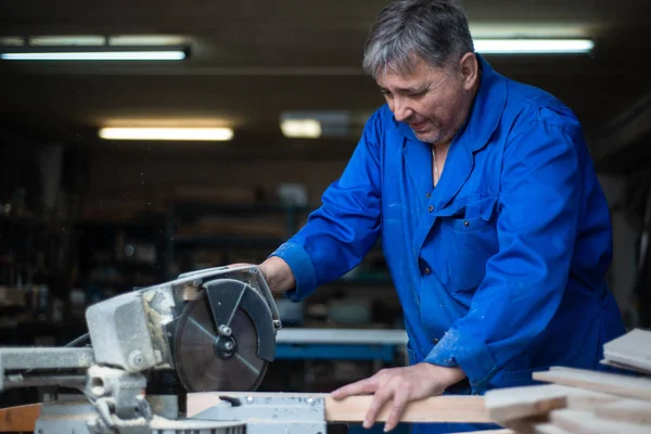 electric saw for sawing boards, the worker saws a wooden board in the workshop