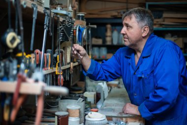 Bir olgun adam marangoz Tulum içinde Araçlar atölye seçer.