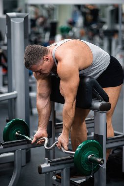 Spor salonunda büyük atletik adam trenler. Eğitim pazı ile tezgah üzerinde bir halter