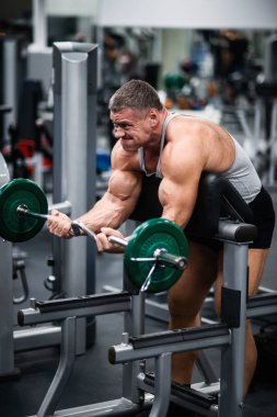 Spor salonunda büyük atletik adam trenler. Eğitim pazı ile tezgah üzerinde bir halter