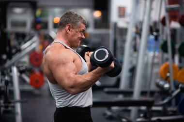 Spor salonunda büyük atletik adam trenler. Eğitim pazı bir dumbbells ile