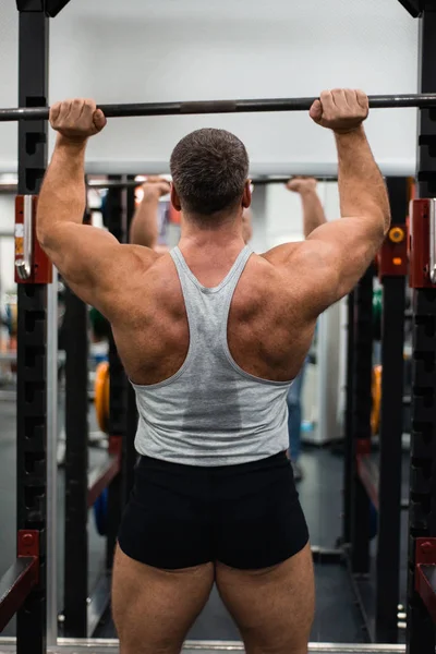 Stor Muskulös Man Tränar Axlarna Med Skivstång Gymmet Hälsa Och — Stockfoto