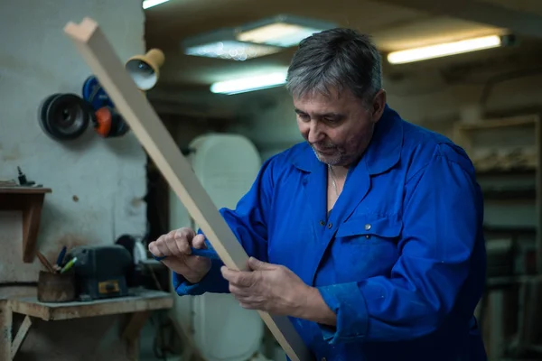 Carpenter at work at his workshop, wood processing on a woodworking machine in worshop