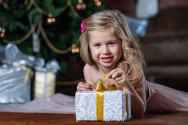 Noel ağacı arka plan katta yatan Noel hediye kutusu ile mutlu gülümseyen kız