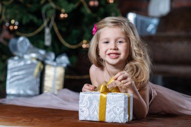 Noel ağacı arka plan katta yatan Noel hediye kutusu ile mutlu gülümseyen kız