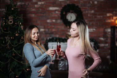 İki genç ve güzel kız arkadaşı veya kız kardeşim Noel birlikte evde şampanya ile el kutlamak