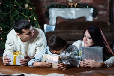 Mutlu aile ile Noel ağacı arka plan üzerinde hediye kutuları yerde yatarken