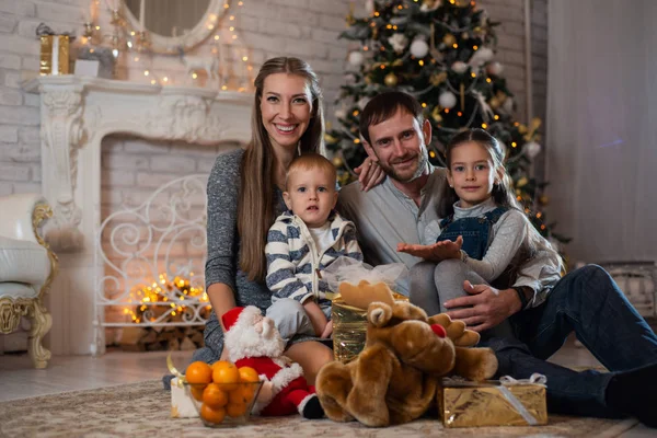 Noel ile dekore edilmiş Noel ağacı hediye kutuları arka planda mutlu bir aile fotoğrafı. Aile yeni yıl kutluyor