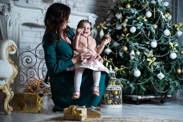 Merry Christmas and happy holidays. Beautiful mother and daughter having fun near the Christmas tree with gifts