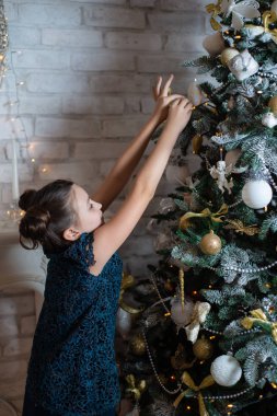 Mutlu yeni yıl arifesinde Noel ağacı şömine yakın kız süsle