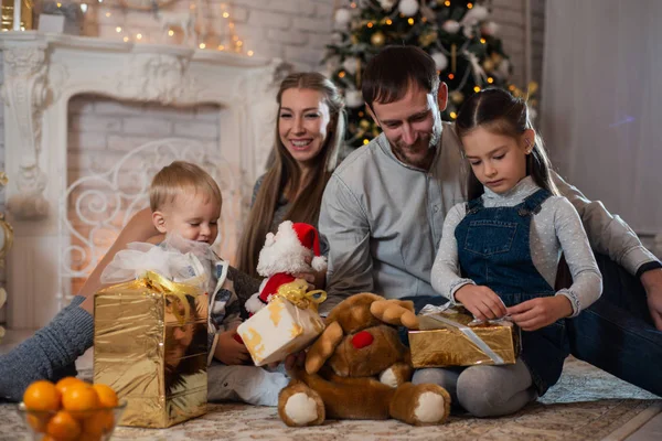 Christmas photo of happy family with gift boxes on the background of decorated Christmas tree. Family celebrates New year