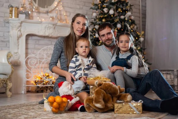 Christmas photo of happy family with gift boxes on the background of decorated Christmas tree. Family celebrates New year