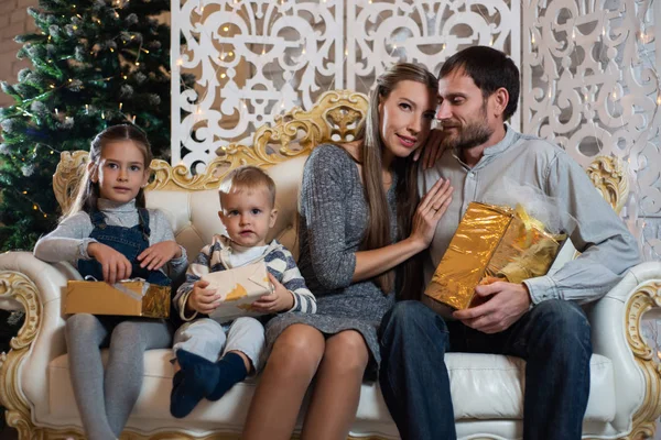 Christmas photo of happy family with gift boxes on the background of decorated Christmas tree. Family celebrates New year