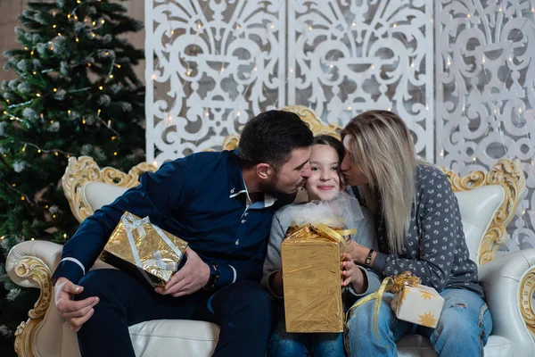 Christmas photo of happy family with gift boxes on the background of decorated Christmas tree. Family celebrates New year