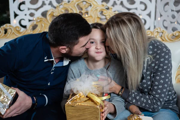 Christmas photo of happy family with gift boxes on the background of decorated Christmas tree. Family celebrates New year