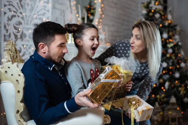 Christmas photo of happy family with gift boxes on the background of decorated Christmas tree. Family celebrates New year
