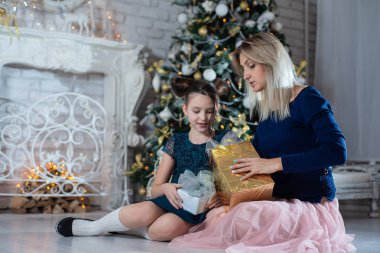 Mutlu Noeller ve mutlu tatiller. Güzel anne ve kızı ile hediyeler Noel ağacı yakın: