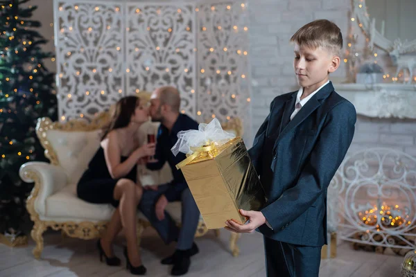 Hijo Sosteniendo Regalo Navidad Sus Manos Fondo Los Padres Felices — Foto de Stock