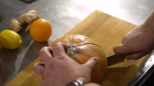 Chef-kok snijdt grote pompoen doormidden in de keuken — Stockvideo