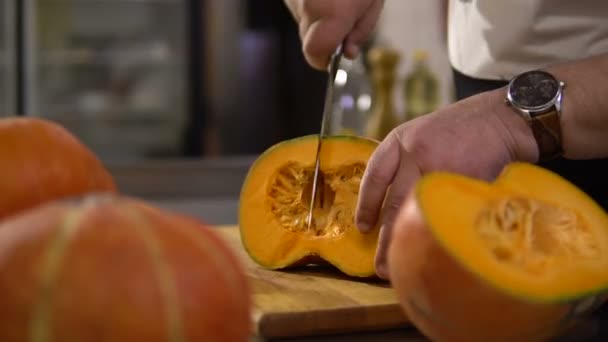 Chef cuts a large pumpkin in the kitchen to prepare a delicious dish — Stock Video