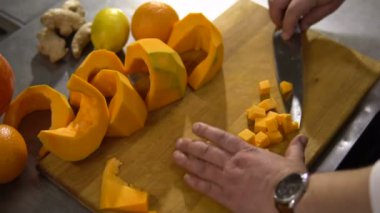 Şef mutfakta büyük bir kabak çorba pişirmek için küçük parçalar yakın çekim keser.