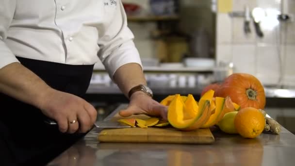 Chef prepara uma grande abóbora na cozinha, cortando a casca para preparar um delicioso prato — Vídeo de Stock