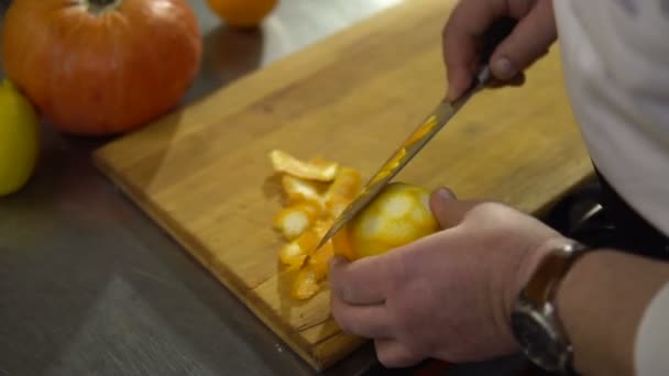 Cook καθαρίζει πορτοκαλί closeup. Τα χέρια με ένα μαχαίρι Κόβουμε τις φλούδες των φρούτων — Αρχείο Βίντεο