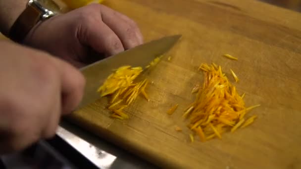 Kocken skär apelsinskal i små bitar närbild — Stockvideo