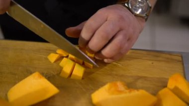Şef mutfakta büyük bir kabak çorba pişirmek için küçük parçalar yakın çekim keser.