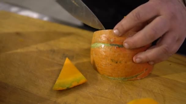 Chef prepara una calabaza grande en la cocina, cortando la cáscara de cerca para preparar un delicioso plato — Vídeo de stock