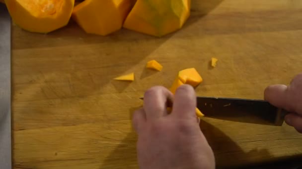 Chef coupe une grande citrouille dans la cuisine en petits morceaux gros plan pour faire cuire la soupe — Video