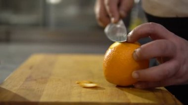 Cook turuncu yakın çekim temizler. Meyve kabuğu elinde bir bıçak ile kesmek