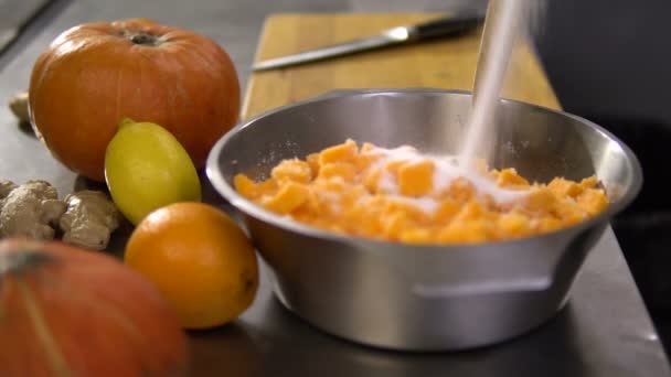 Koch gießt Zucker in einen Teller mit in kleine Stücke geschnittenem Kürbis — Stockvideo