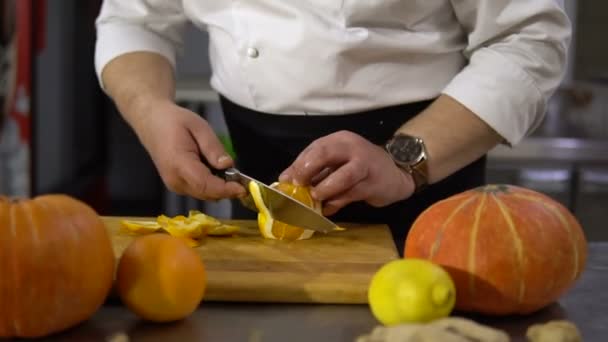 Cook limpia naranja en la cocina. Manos cuchillo cortar la cáscara de la fruta — Vídeos de Stock