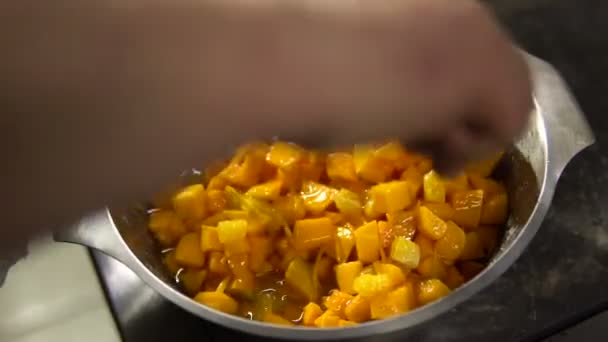 Шеф-повар готовит тыквенное блюдо, смешивая кусочки в тарелке с ложкой — стоковое видео