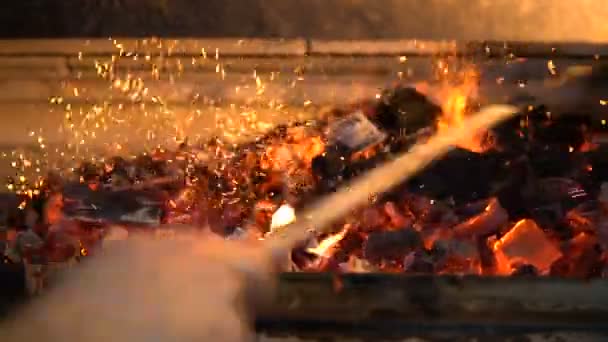 Χέρι με ένα ραβδί αναμιγνύει τα αναμμένα κάρβουνα για το φούρνο closeup — Αρχείο Βίντεο