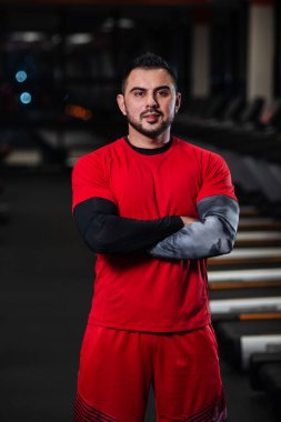 Kırmızı giysili spor salonunda kameraya poz büyük kaslar, yakışıklı adamla