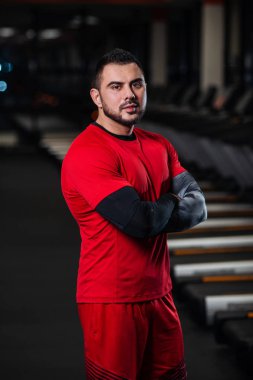 Kırmızı giysili spor salonunda kameraya poz büyük kaslar, yakışıklı adamla