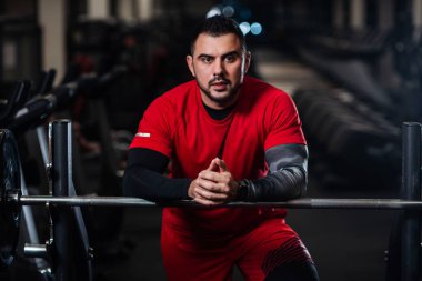 Kırmızı giysili spor salonunda kameraya poz büyük kaslar, yakışıklı adamla